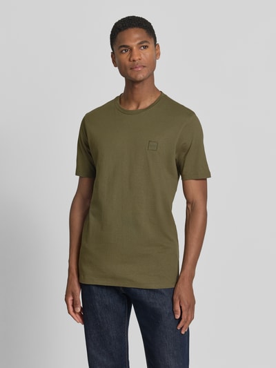 Männermodel trägt Regular Fit T-Shirt aus reiner Baumwolle Modell 'TALES' von BOSS Orange in Olivgrün, unifarben, Label Patch, Ganzkörperansicht von vorne.