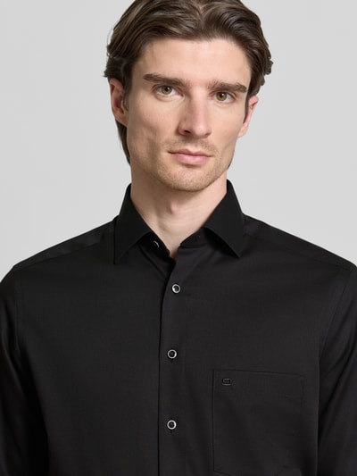 Männermodel trägt Regular Fit Businesshemd aus Baumwolle mit Kentkragen von OLYMP, schwarze Farbe, Brusttasche, Nahaufnahme Oberkörper.