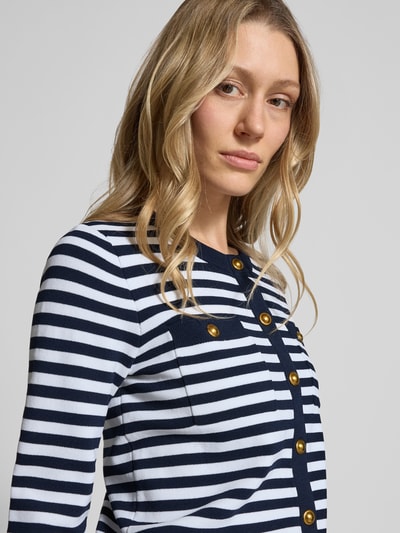 Frauenmodel trägt Strickjacke mit Rundhalsausschnitt und Knopfleiste von MICHAEL Michael Kors, marine-weiß gestreift, Nahaufnahme Oberkörper. Viskose-Mix mit Stretch-Anteil, Regular Fit, sichtbare goldene Knöpfe, weiche Stricktextur.