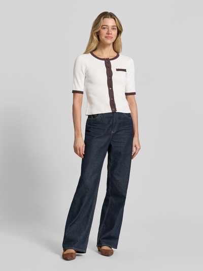 Frauenmodel trägt Slim Fit Cardigan in Strick-Optik von More & More, cremefarben mit braunen Details, reine Baumwolle, Halbarm, Ganzkörperansicht von vorne.