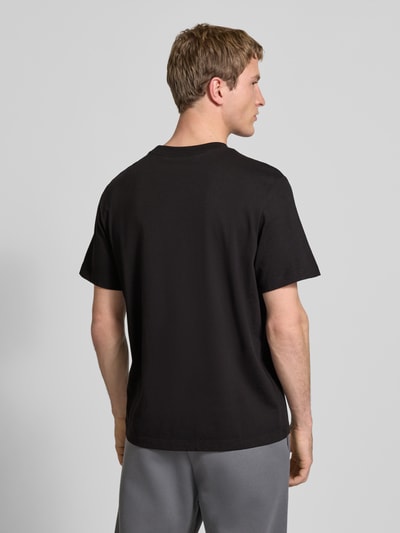 Männermodel trägt T-Shirt mit Label-Print und Rundhalsausschnitt von Calvin Klein Jeans in Schwarz, Reine Baumwolle, Regular-Fit, Rückenlänge 70 cm, Ganzkörperansicht Rückansicht.