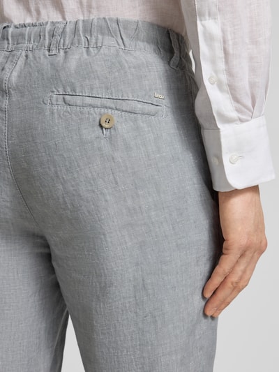 Männermodel trägt Slim Fit Leinenhose aus reinem Leinen Modell 'Fabio' von Brax, hellgrau, Label-Applikation, Detailaufnahme Rückansicht.