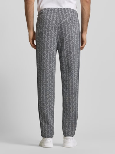 Männermodel trägt Regular Fit Sweathose mit Baumwoll-Anteil von Lacoste, Optik: Allover-Muster, Kontraststreifen, Sweat, Ganzkörperansicht Rückansicht.