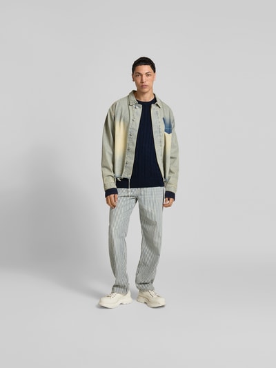 Männermodel trägt Slim Fit Pullover in Strick-Optik von Filippa K aus reiner Baumwolle, dunkelblau, Feinstrick, Ganzkörperansicht von vorne.