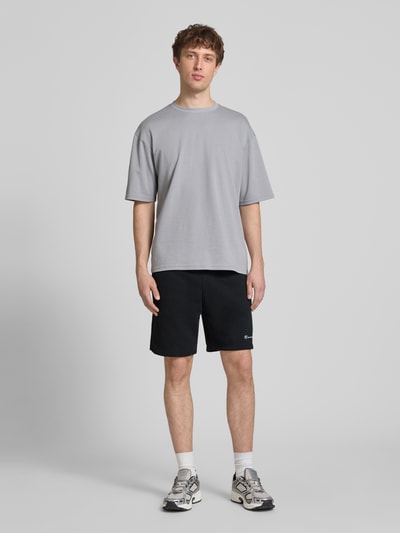 Mannenmodel draagt Shorts met elastische tailleband en label-stitching van CHAMPION, katoenmix, regular fit, zwart, volledige lichaamsvoorzijde.