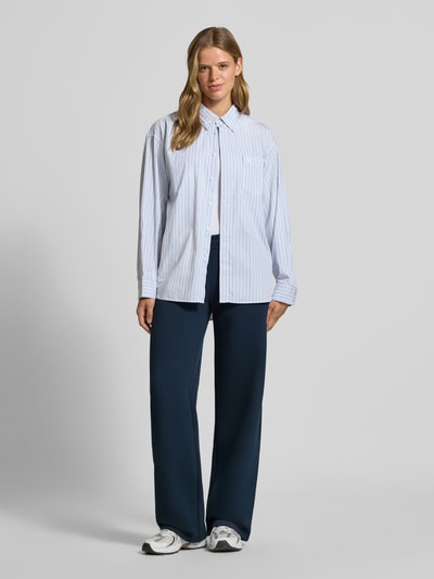 Frauenmodel trägt dunkelblaue Sweathose mit geradem Bein von REVIEW aus Baumwoll-Mix, elastischer Bund, Logo-Print, Ganzkörperansicht von vorne.