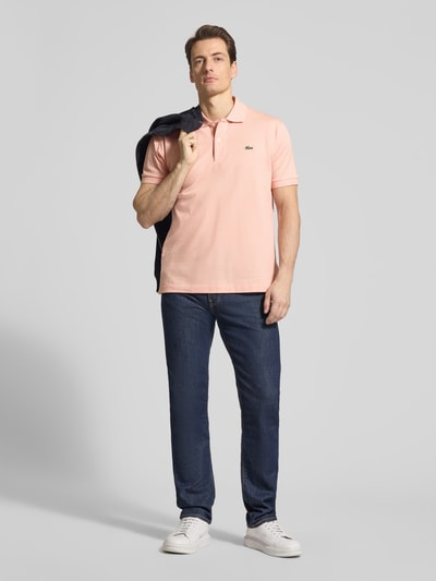 Männermodel trägt Regular Fit Poloshirt aus reiner Baumwolle von Lacoste, Optik: Unifarben, Piqué-Textur, Ganzkörperansicht von vorne.