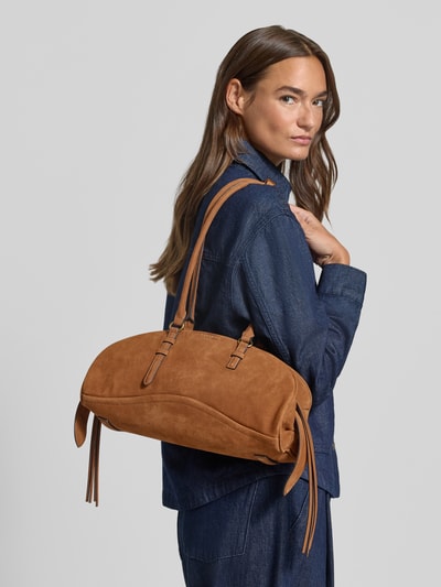 Frauenmodel trägt Pochette aus Leder Modell 'CAPRI' von LIEBESKIND BERLIN in warmem Braun, sichtbare Label-Details, Ganzkörperansicht Rückansicht. Hauptfach mit Reißverschluss, Tragehenkel, Innentasche und Schulterriemen sind zu erkennen.