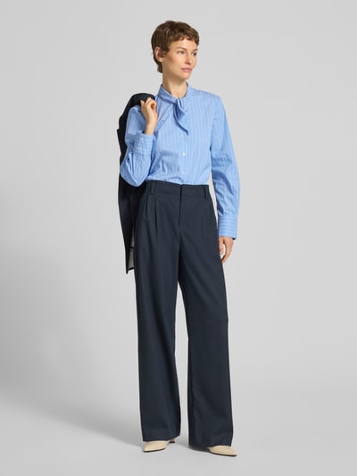Vrouwenmodel draagt Slim Fit Schluppenbluse mit Knopfleiste van Stefanel in lichtblauw met fijne strepen, katoenmix met stretch, opstaande kraag, knoopsluiting, lengte rug maat S 60 cm, mouwlengte maat S 62 cm, voorkant volledige lichaamsperspectief.