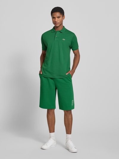 Męski model nosi Regular Fit Poloshirt aus reiner Baumwolle Modell 'CORE' od Lacoste, intensywna zieleń, gładka faktura, Ganzkörperansicht von vorne. Koszulka polo w kontekście Lacoste.