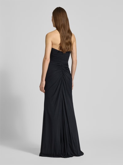 Frauenmodel trägt Regular Fit Abendkleid mit Gehschlitz von Mascara in Schwarz, schulterfreies Design, Mesh, Raffungen, Rückansicht, Ganzkörperansicht.