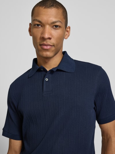 Männermodel trägt Regular Fit Poloshirt reiner Baumwolle Modell 'COLE' von SELECTED HOMME in Dunkelblau, Struktur-Jersey, Nahaufnahme Oberkörper.