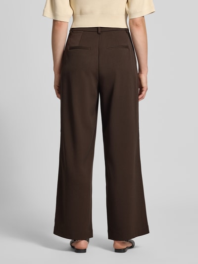Frauenmodel trägt Baggy Fit Stoffhose mit gelegten Falten Modell 'Henrika' von MSCH COPENHAGEN in Dunkelbraun, Material-Mix mit Viskose-Anteil, Ganzkörperansicht Rückansicht.
