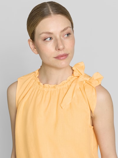 Frauenmodel trägt Regular Fit Bluse aus Viskose-Mix mit Leinen-Anteil von Christian Berg Woman in zartem Gelb, Zierschleife, Stehkragen mit Rüschenbesatz, Ärmelloses-Design, Nahaufnahme Oberkörper.