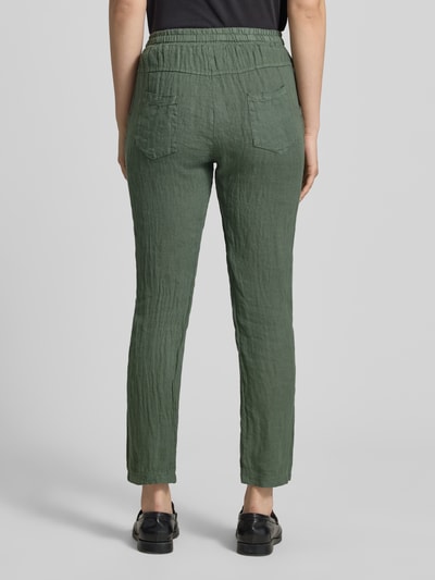 Frauenmodel trägt Leinenhose mit elastischem Bund Modell 'Pa44uline' von ZABAIONE in Grün, reine Leinenstruktur, Ganzkörperansicht Rückansicht.