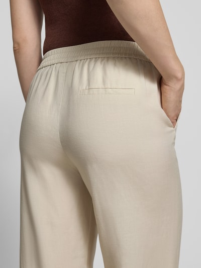 Frauenmodel trägt Stoffhose aus Lyocell-Mix mit elastischem Bund von Comma, beige, glatte Oberfläche, Gesäßtasche, Nahaufnahme Rückansicht. Relaxed-Fit, Lyocell-Mix mit Leinen-Anteil, Bundweite Größe 36/32: 39 cm, Innenbeinlänge: 78 cm.