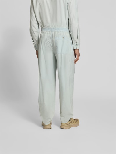 Männermodel trägt Relaxed Fit Sweatpants in Denim-Optik von Kenzo aus reiner Baumwolle, elastischer Bund, Knopf- und Reißverschluss, hellblaue Struktur, Ganzkörperansicht Rückansicht.