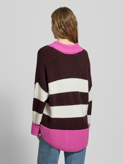 Frauenmodel trägt Oversized Strickpullover mit Polokragen Modell 'Maya' von OH APRIL, Woll-Mix, breite Streifen, Pink und Braun, Ganzkörperansicht Rückansicht.