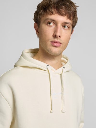 Männermodel trägt Relaxed Fit Hoodie mit Känguru-Tasche van KARL KANI in licht katoenmix met gestikt logo, capuchon met tunnelkoord, Nahaufnahme Oberkörper. Ruglengte maat M: 70 cm, mouwlengte maat M: 68 cm.