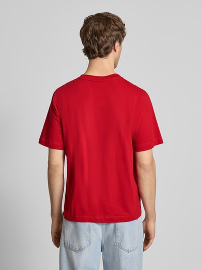 Männermodel trägt rotes T-Shirt mit Label-Stitching Modell 'NORREBRO' von Jack & Jones aus reiner Baumwolle, Ganzkörperansicht Rückansicht.