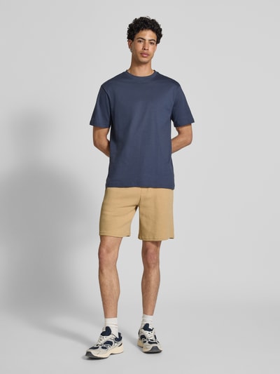 Männermodel trägt Shorts aus Baumwoll-Mix mit Strukturmuster Modell 'KNOX' von Redefined Rebel in Beige, elastischer Bund, Ganzkörperansicht von vorne.