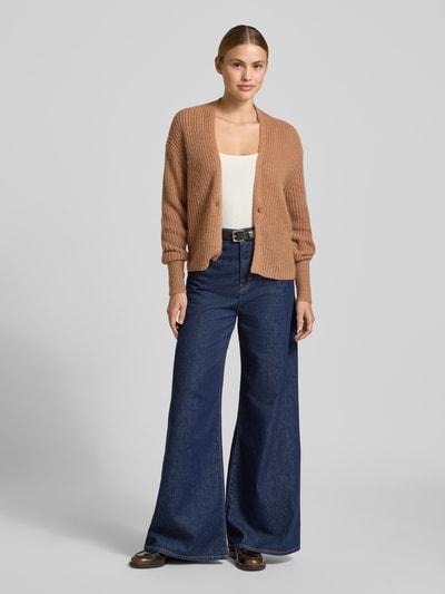 Frauenmodel trägt Regular Fit Cardigan mit Alpaka-Woll-Anteil Modell 'Kanna' von JOOP!, Strick-Optik, V-Ausschnitt, Knopfverschluss, Material-Mix, hellbraune Farbe, angenehme Textur, Rückenlänge 63 cm, Ärmellänge 63 cm, Ganzkörperansicht von vorne.