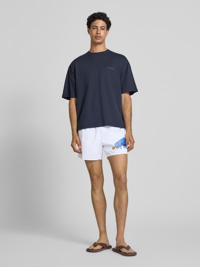 Männermodel trägt Badeshorts mit Motiv-Print von Hugo Blue, Optik: Unifarben, Tunnelzug, Gesäßtasche, Popeline, Ganzkörperansicht von vorne.