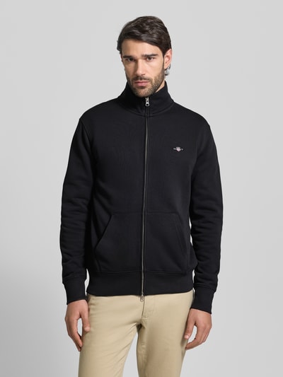 Männermodel trägt schwarze Regular Fit Sweatjacke mit Stehkragen Modell 'Gield' von Gant, Kängurutasche, Logo, Baumwoll-Mix, Ganzkörperansicht von vorne