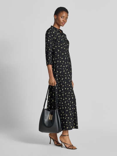 Frauenmodel trägt Maxikleid aus reiner Viskose Modell 'Savanna' von YAS mit floraler Allover-Print-Optik, tailliert, 3/4-Arm, Ganzkörperansicht von vorne.