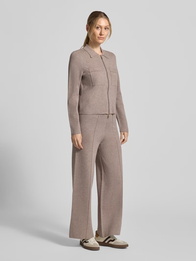 Vrouwenmodel draagt Regular Fit gebreid jack uit zuiver viscose van Christian Berg Woman in lichtbruin met platte kraag, tweewegritssluiting, twee opgestikte borstzakken, losse pasvorm, ruglengte maat S 53 cm, mouwlengte maat S 61 cm. Ganzekörperaanzicht van voren.