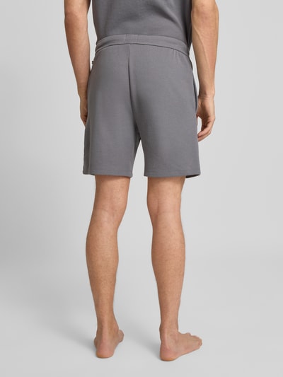 Männermodel trägt Regular Fit Sweatshorts aus Baumwoll-Mix Modell 'WAFFLE' von BOSS in Grau mit Strukturmuster, Ganzkörperansicht Rückansicht.