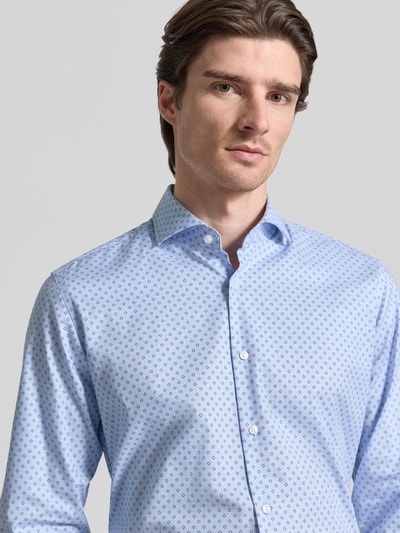 Männermodel trägt Regular Fit Businesshemd aus Baumwolle mit Kentkragen Modell 'JOE' von BOSS mit Allover-Muster in Hellblau, Nahaufnahme Oberkörper.