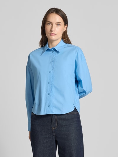 Modelka kobieca nosi Regular Fit Hemdbluse mit verlängerter Rückseite von JAKE*S STUDIO WOMAN z czystej bawełny w kolorze jasnoniebieskim, klasyczny kołnierzyk koszulowy, długie rękawy ze sportowymi mankietami, pełny pasek guzików, wydłużony tył, tekstura gładka, widok całej sylwetki z przodu.