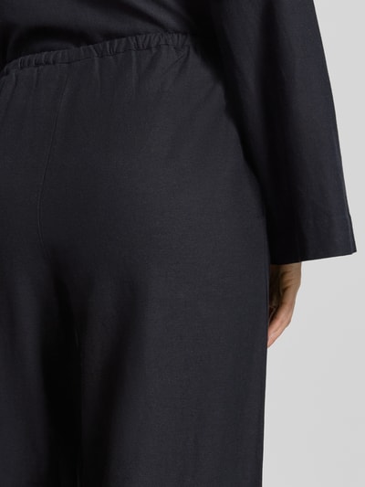 Frauenmodel trägt Stoffhose aus Viskose-Mix Modell 'PRISILLA' von Vila, dunkel, matte Struktur, Eingrifftaschen, Detailaufnahme Rückansicht. Kontext: Damen Stoffhose, Leinen-Viskose-Mix, Wide Leg, Tunnelzug, Bundweite 35 cm, Innenbeinlänge 82 cm bei Größe 36.