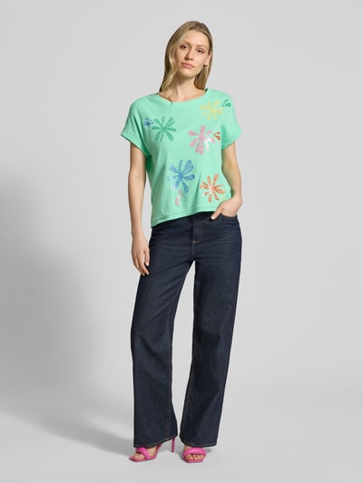 Frauenmodel trägt T-Shirt aus Baumwoll-Leinen-Mix mit Stitchings von Milano Italy, grün mit bunten Blüten, Regular-Fit, Rundhalsausschnitt, Rückenlänge bei Größe S 51 cm, Ganzkörperansicht von vorne.