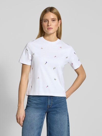 Kobiece model prezentuje T-Shirt mit Blumenstickerei od Christian Berg Woman, biała bawełna, prosty krój, haftowane kwiaty, półrękaw, okrągły dekolt, widok całej sylwetki z przodu.
