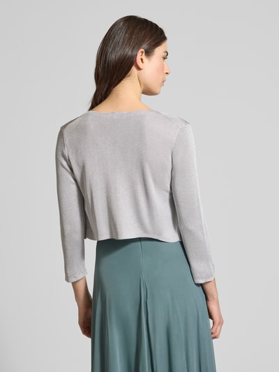 Frauenmodel trägt Regular Fit Bolero aus Viskose-Mix in Strick-Optik von Jake*s Cocktail mit Glitzer-Optik, Rückenlänge 39 cm, Ganzkörperansicht Rückansicht.