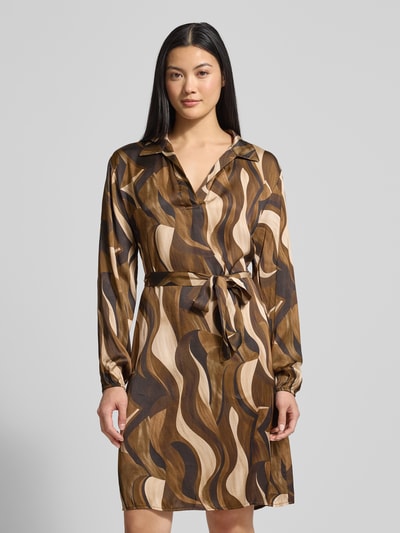 Modelka kobieca nosi Minikleid aus Viskose mit Bindegürtel Modell 'Be44atricee' od ZABAIONE w odcieniach brązu i beżu, wzór falisty, A-linia, kołnierz klasyczny, dekolt V, wiązany pasek, długość mini, widok całej sylwetki z przodu.