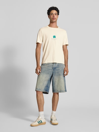 Männermodel trägt Regular Fit T-Shirt mit Logo-Print Modell 'Eres' von Jack & Jones aus Reine Baumwolle, Rundhalsausschnitt, Ganzkörperansicht von vorne