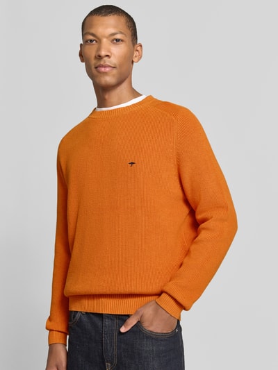 Männermodel trägt Regular Fit Strickpullover aus reiner Baumwolle von Fynch-Hatton in Orange mit Label-Detail und elastischen Abschlüssen, Nahaufnahme Oberkörper.