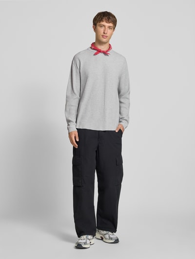 Männermodel trägt Relaxed Fit Langarmshirt aus reiner Baumwolle von Levi's®, hellgrau, kombiniert mit dunkler Cargo-Hose und Sneakers, Ganzkörperansicht von vorne, Herren Langarmshirt von Levi's®.