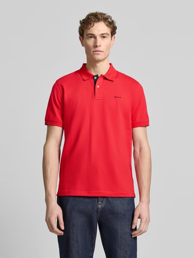 Männermodel trägt Regular Fit Poloshirt mit Logo-Stitching von Gant in Rot, elastischer Baumwoll-Mix, Polokragen, Ganzkörperansicht von vorne.