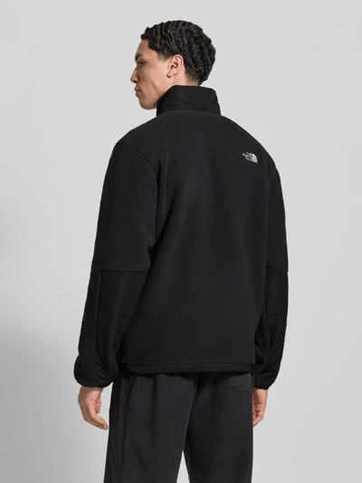 Męskimodel nosi kurtkę z polaru Fleecejacke mit Napoleontasche Modell 'YUMIORI' od The North Face, czarny, prosty krój, długość tyłu 70 cm, długość rękawów 70 cm, wpuszczane kieszenie, elastyczne wykończenia, Ganzkörperansicht Rückansicht.