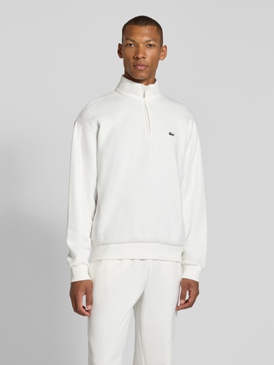 Männermodel trägt Regular Fit Troyer aus Baumwoll-Mix von Lacoste in Weiß, glatte Struktur, Ganzkörperansicht von vorne, Herren Troyer.