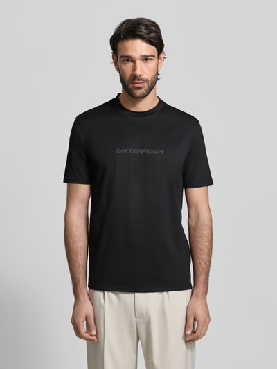 Männermodel trägt Regular Fit T-Shirt mit Logo-Detail von Emporio Armani in Schwarz aus reiner Baumwolle, Ganzkörperansicht von vorne.