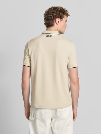 Męski model nosi Regular Fit Poloshirt aus Baumwoll-Mix model 'PADDY PRO' od BOSS Green, jasny beż, gładka tekstura, czarne lamówki, całkowity widok z tyłu.