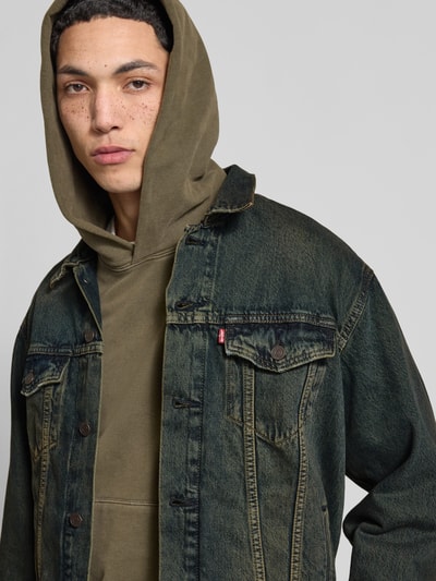 Mężczyznamodel nosi Relaxed Fit Jeansjacke aus reiner Baumwolle Modell 'TRUCKER' von LEVI'S®, denim, szwy, nity, kieszenie, wykładany kołnierz, listwa guzikowa, wyhaftowane logo, Ganzkörperansicht z przodu.