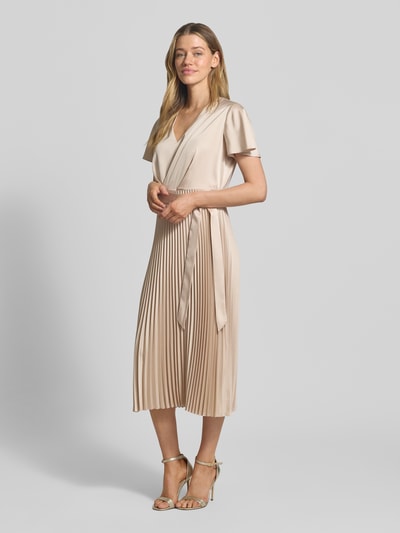 Frauenmodel trägt Midikleid mit Plisseefalten und V-Ausschnitt von comma in Beige, tailliert, Bindegürtel, Material-Mix, Ganzkörperansicht von vorne.