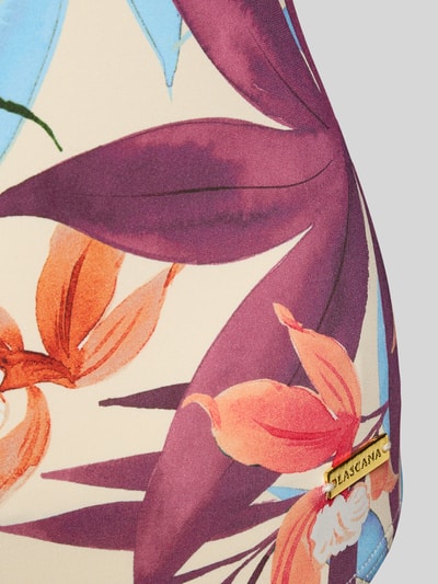Frauenmodel trägt Badeanzug mit rückseitig überkreuzten Trägern Modell 'Imani' von LASCANA, Material-Mix mit Stretch-Anteil, körpernaher Schnitt, V-Ausschnitt, florale Farben, Detailaufnahme.