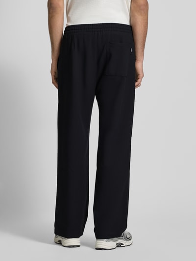 Männermodel trägt Straight Fit Stoffhose mit Viskose-Anteil von REVIEW in Schwarz, elastischer Bund, Gesäßtasche, Ganzkörperansicht Rückansicht.